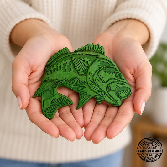 Green engraved bass fish ornament resting on two open palms