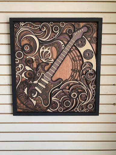 Wooden wall art of a guitar with decorative patterns on a wooden panel background