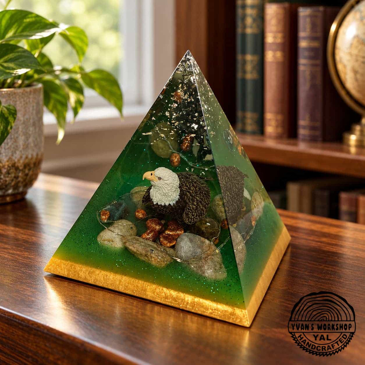 Green and gold resin pyramid containing a bald eagle figurine and decorative stones