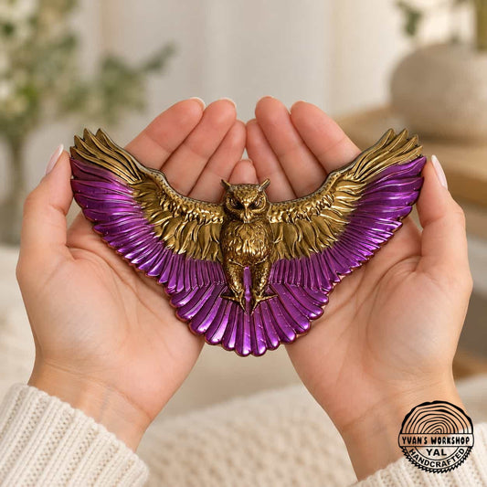Gold and purple spread-wing owl ornament held across two open hands