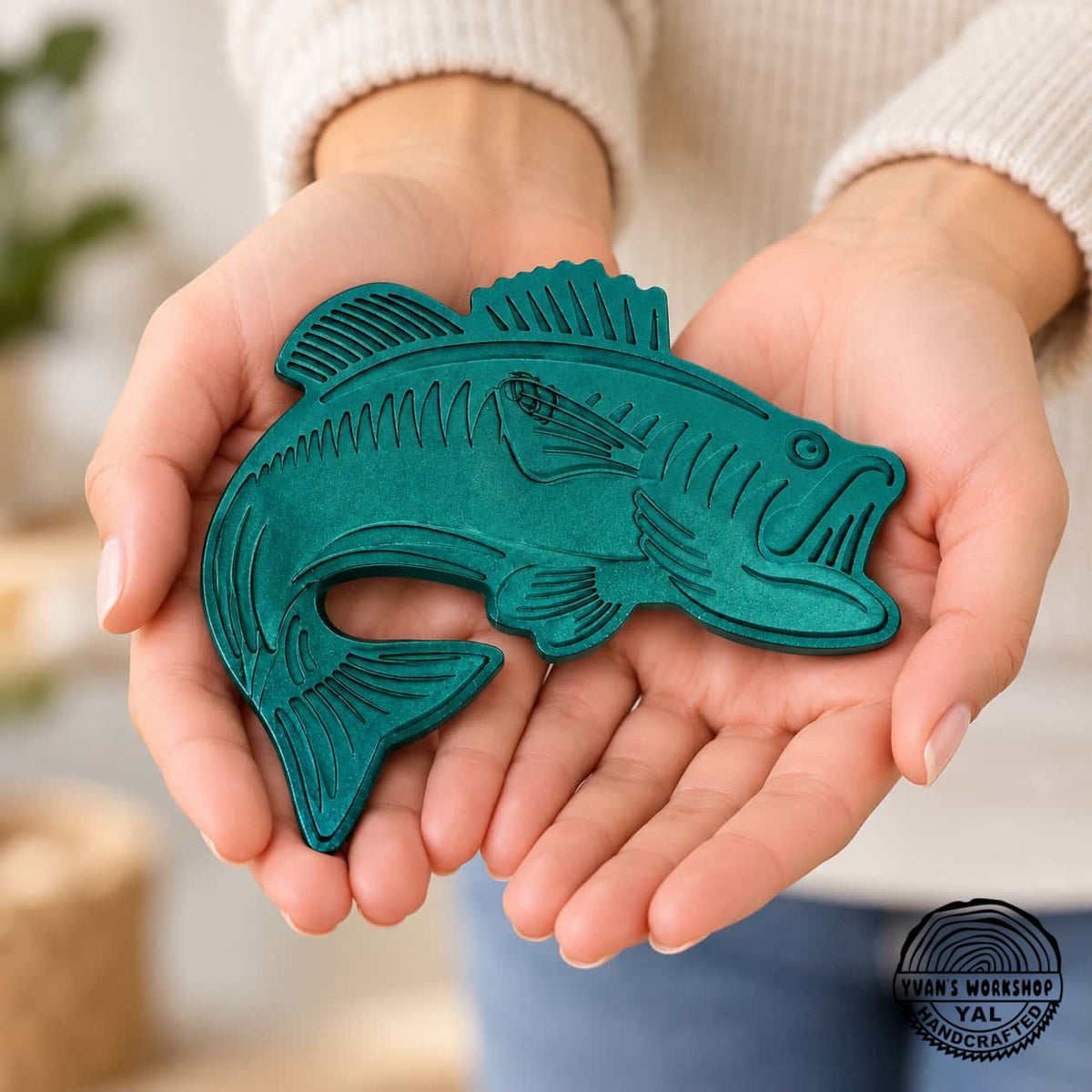 Teal-blue bass fish ornament with a curved tail and engraved details
